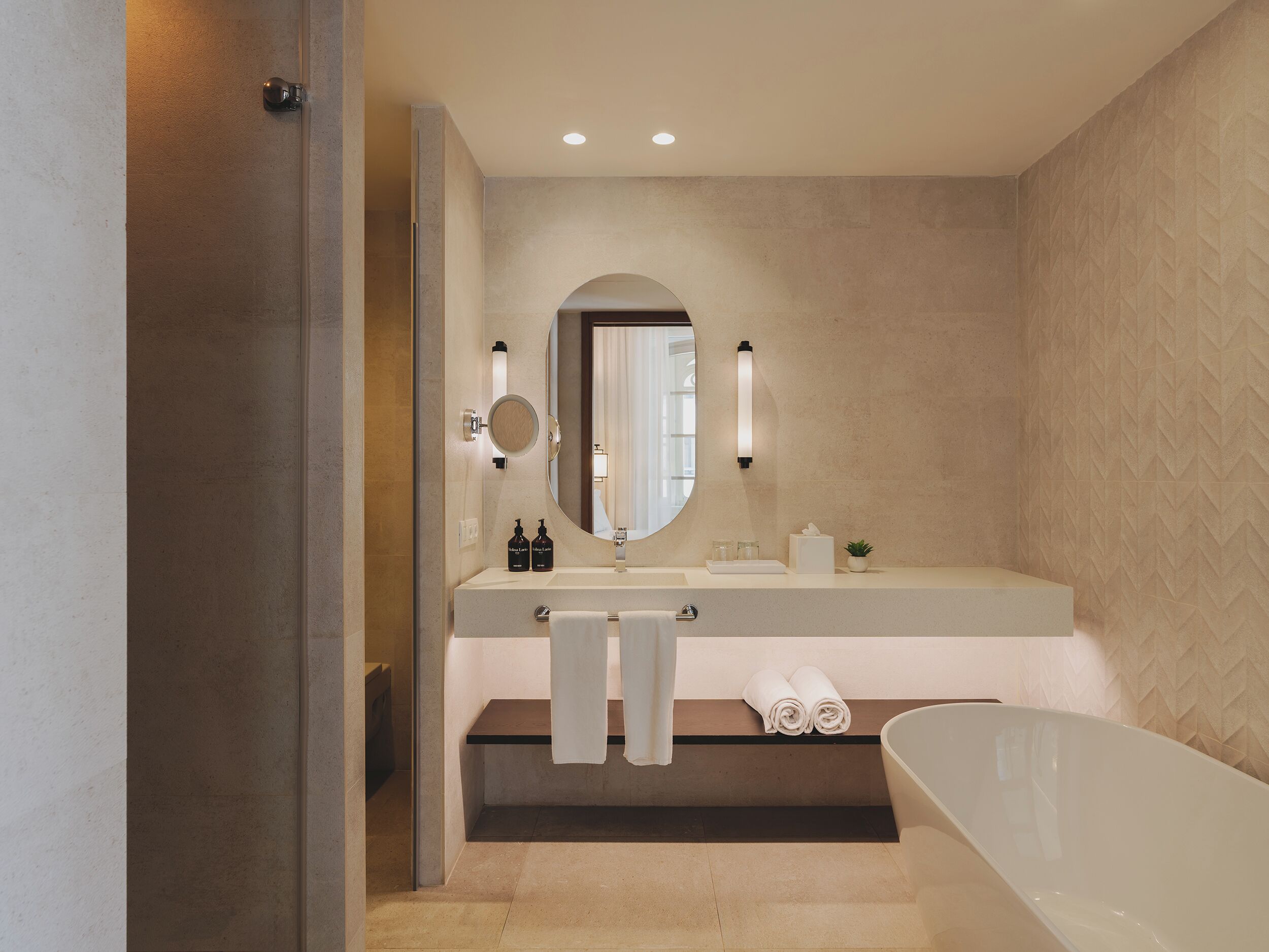 A modern bathroom with a freestanding bathtub, a large mirror, and a vanity with two sinks.