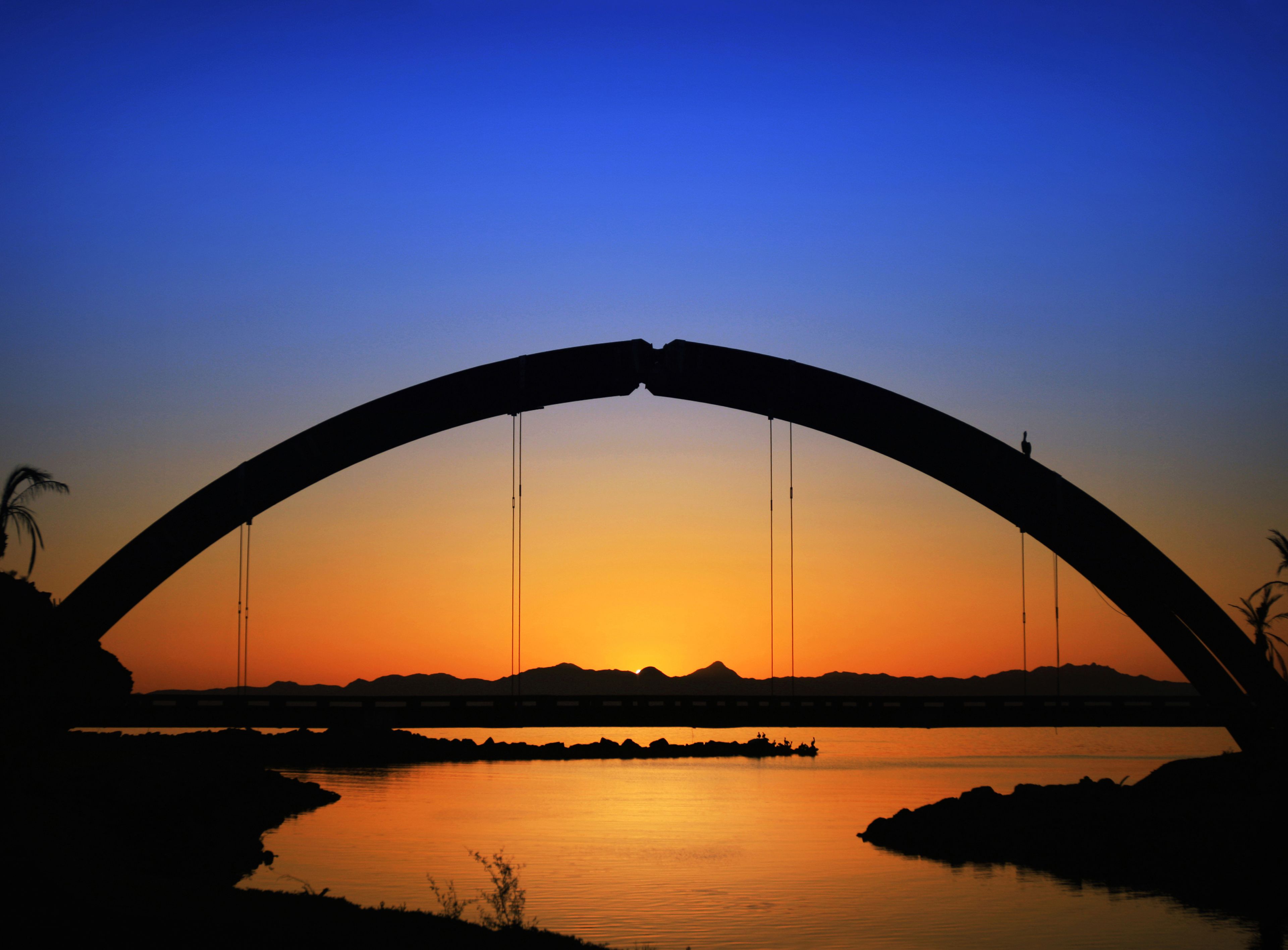 Eine Brücke mit einer gewölbten Bögen vor einem Sonnenuntergangshimmel.