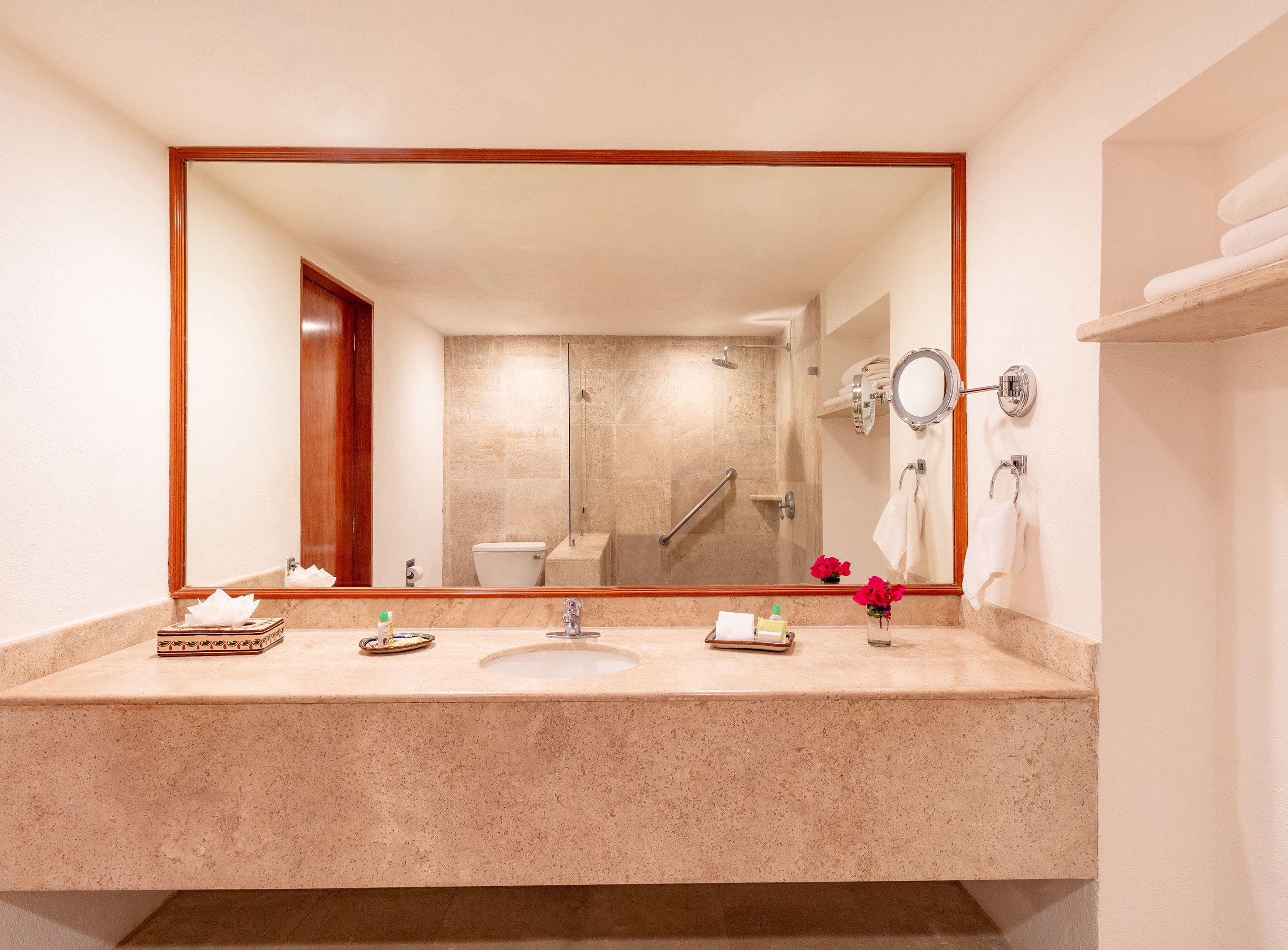 A bathroom with a large mirror, a sink, a toilet, and a shower.