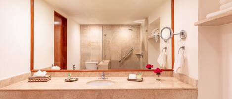 A bathroom with a large mirror, a sink, a toilet, and a shower.