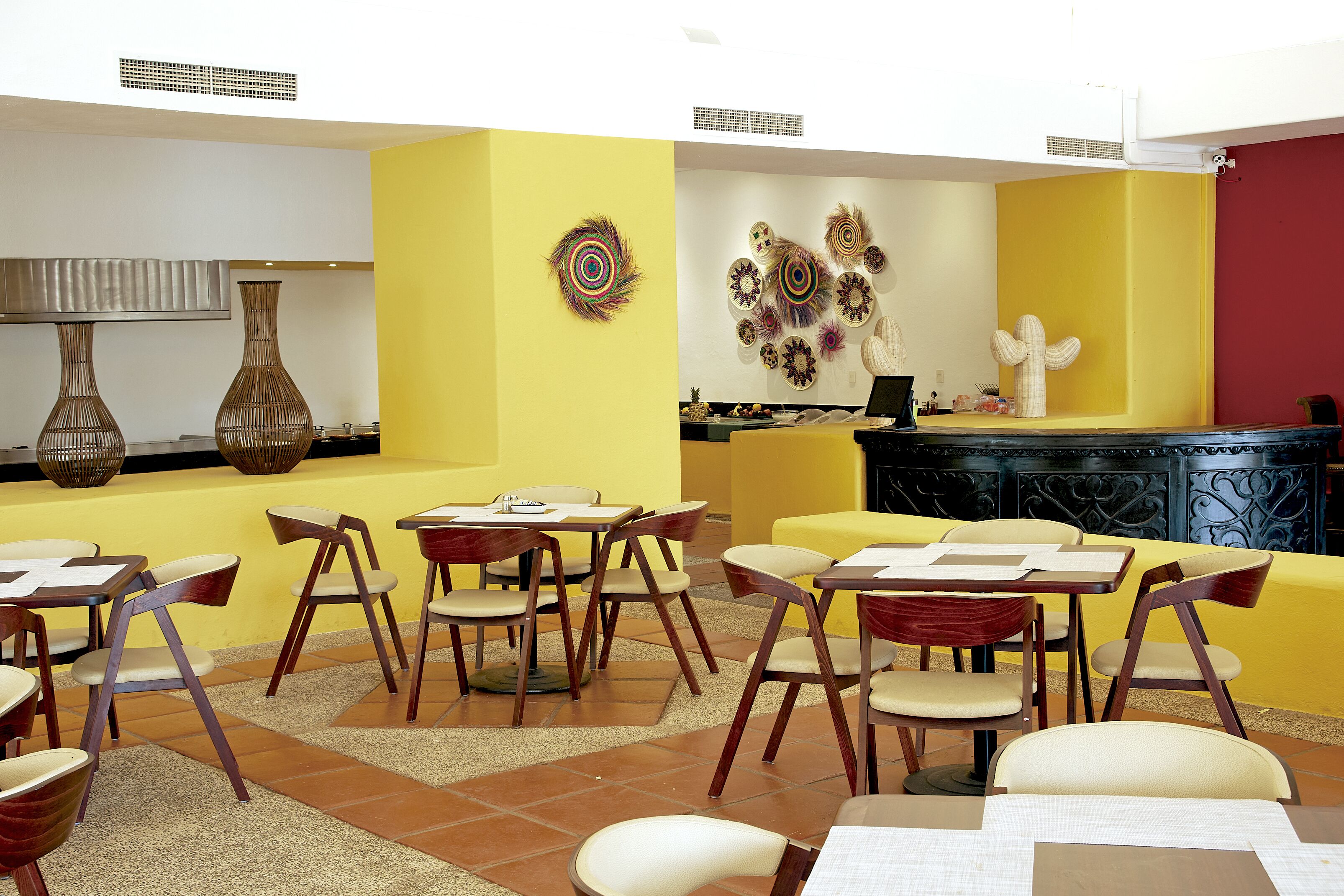 Uma sala de jantar com paredes amarelas, cadeiras de madeira e mesas.