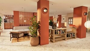 A modern lobby with a sofa, a bookshelf, and a decorative wall panel. - Coral California (Arona)