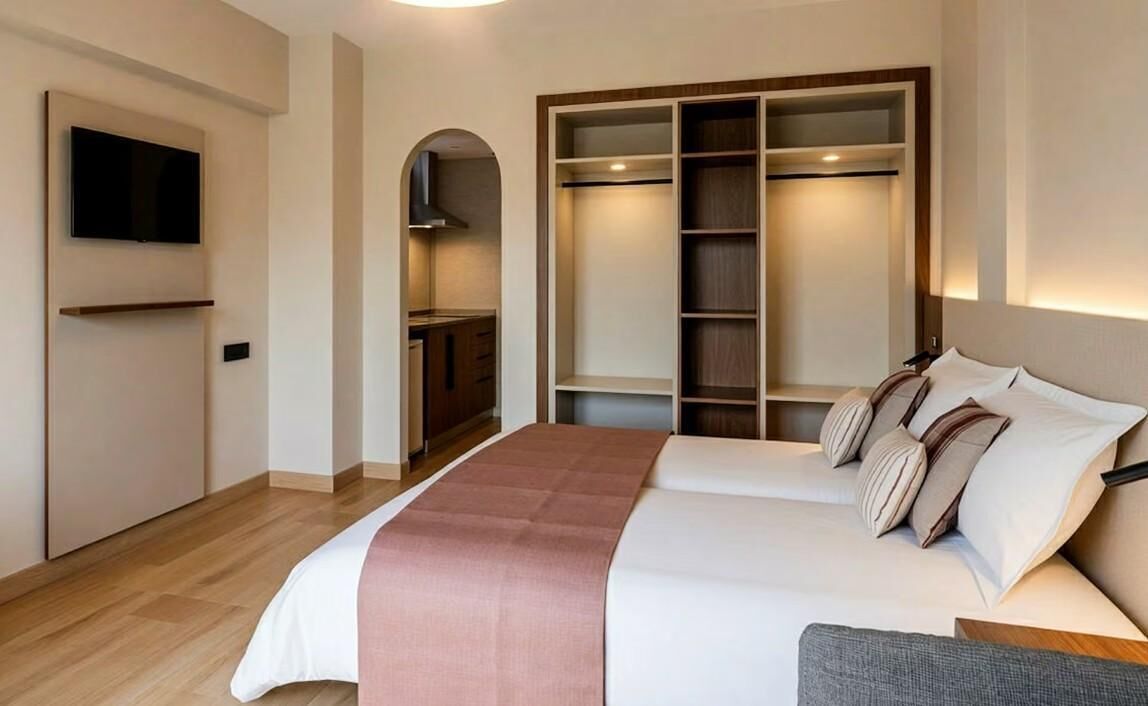 Une chambre d’hôtel équipée d’un lit, d’une télévision, d’une armoire et d’une kitchenette.