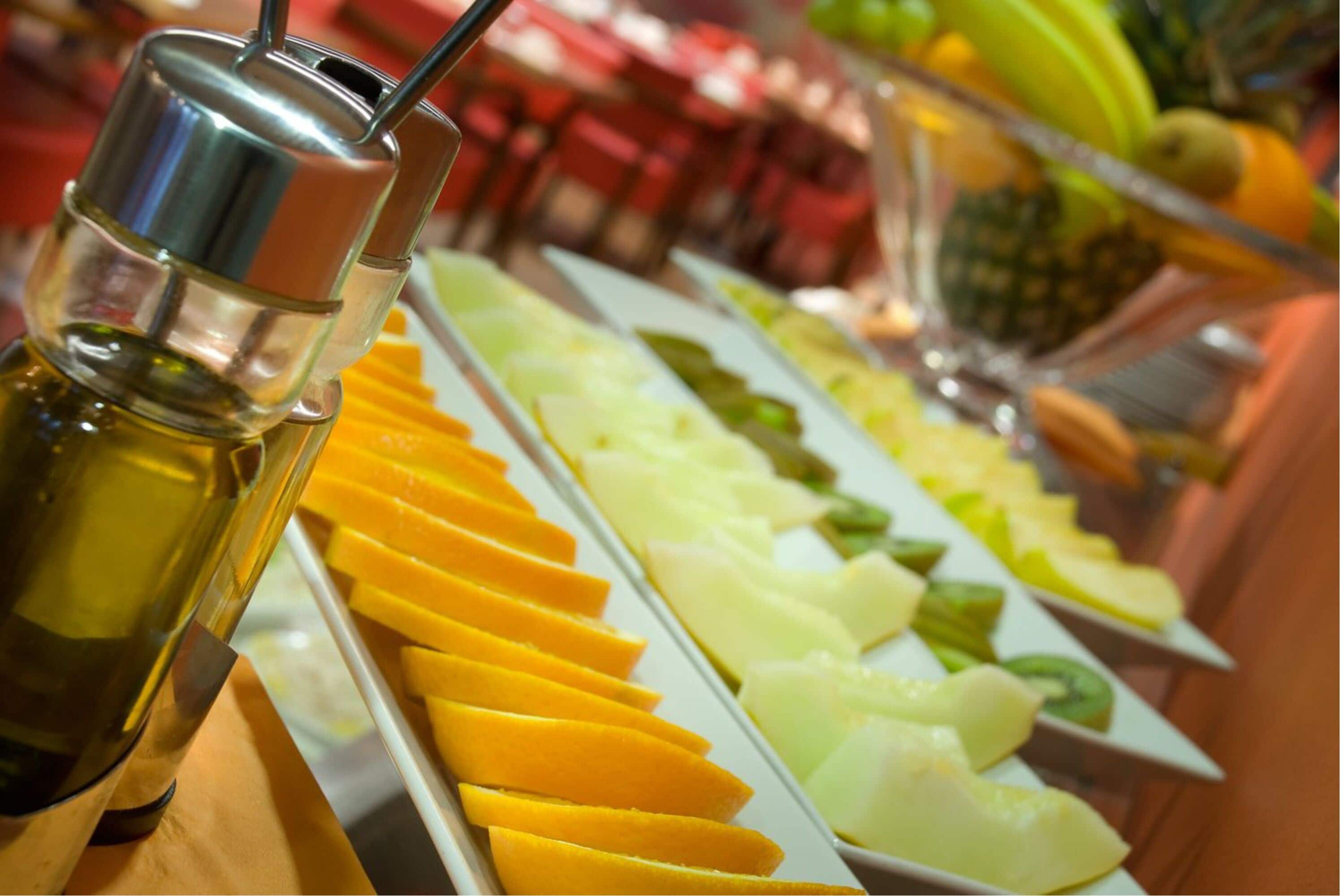A buffet with various fruits and a bottle of juice.