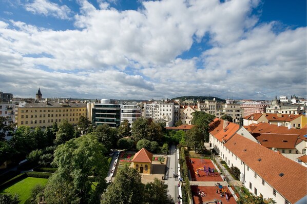 A cityscape with a mix of modern and traditional buildings, a prominent church, and a well-maintained public square with a small pavilion.