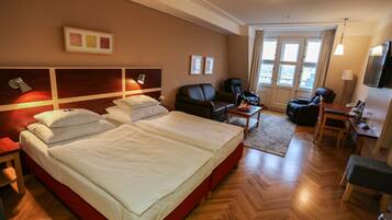 A hotel room with a large bed, a desk, a chair, and a sofa.