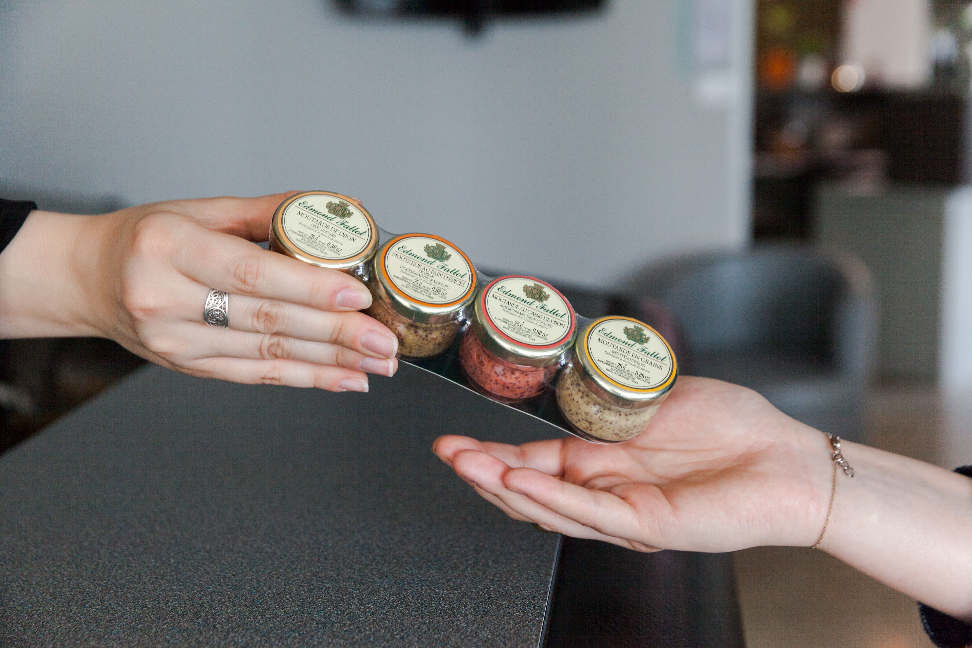 A person holding four jars of jam.