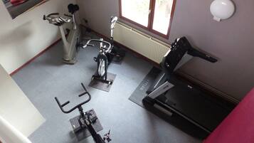 A home gym with stationary bikes, a treadmill, and exercise mats.