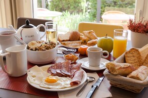 Ett frukostbord med olika sorters mat, en tekanna och en kopp kaffe.