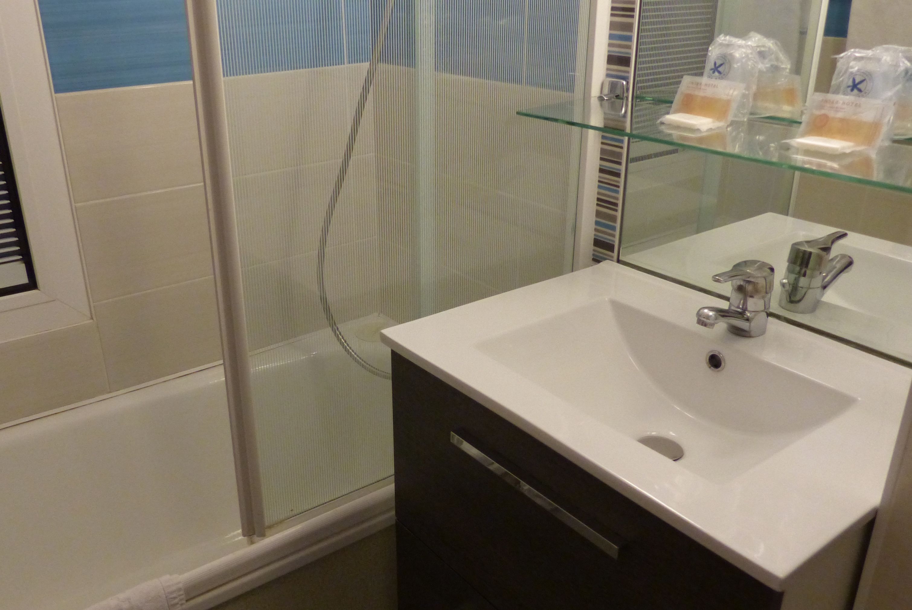 A bathroom with a glass shower enclosure, a white sink, and a mirror.
