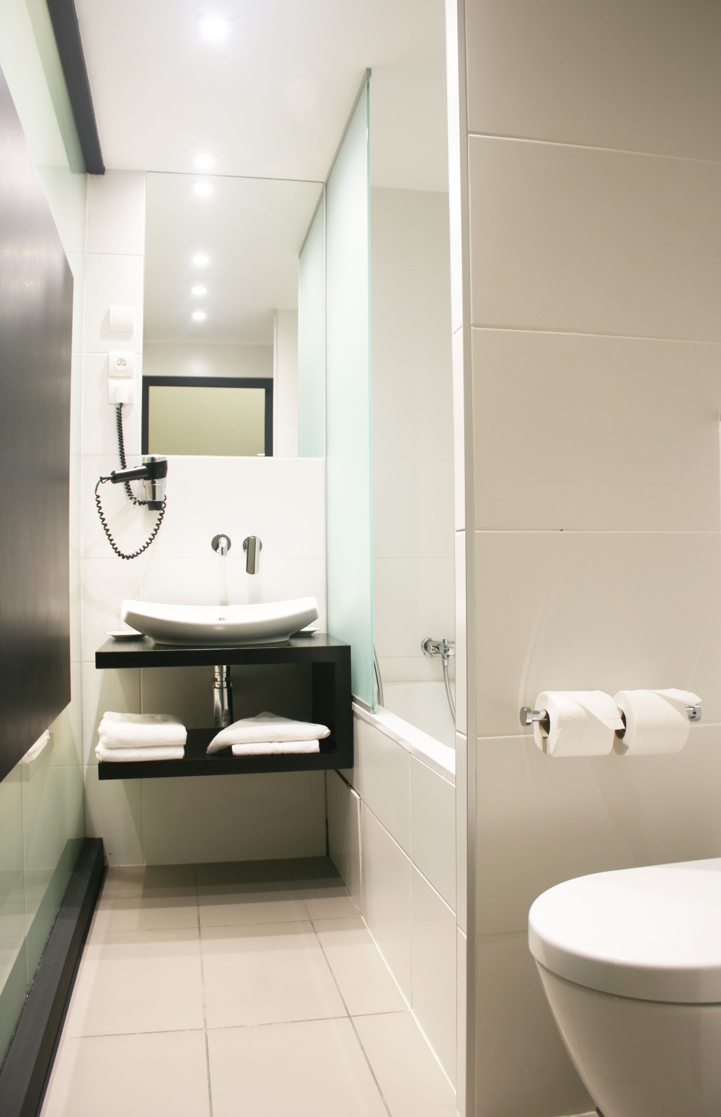 Un baño moderno con lavamanos blanco, un espejo y un inodoro.