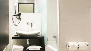 Un baño moderno con lavamanos blanco, un espejo y un inodoro.