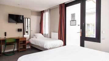 A hotel room with a bed, a desk, a chair, a TV, and a window with curtains.