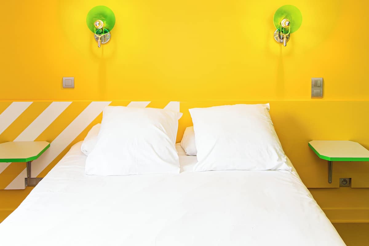 Une chambre avec un lit, deux tables de chevet et un luminaire fixé au mur.