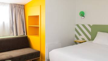 Een hotelkamer met een bed, een bank, een klein tafeltje en een stoel.