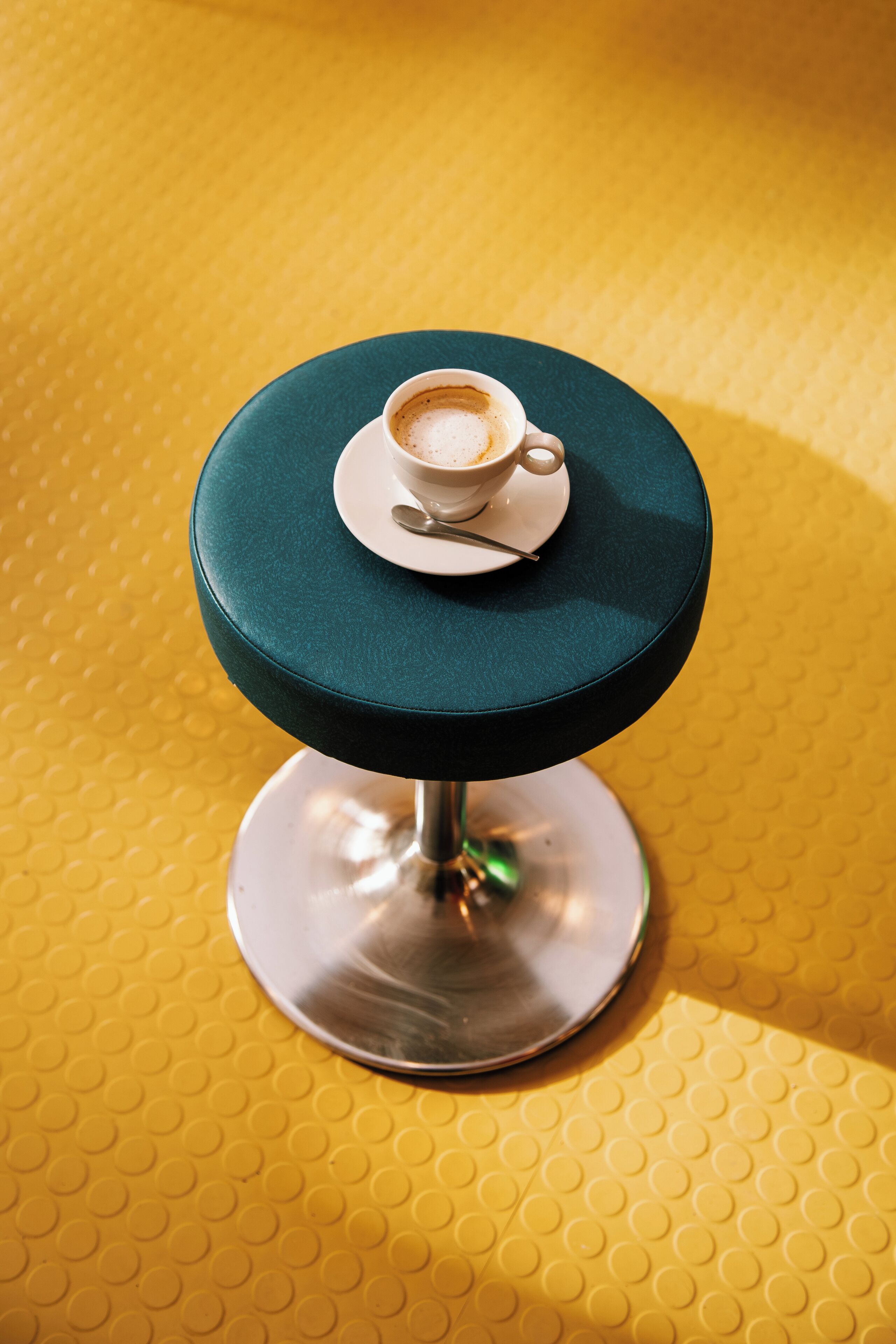 A round table with a green top and a cup of coffee on it.
