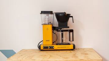 A compact coffee maker on a wooden table.