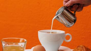 Une table mise pour le petit-déjeuner avec une tasse de café, un croissant et un verre de jus d’orange.