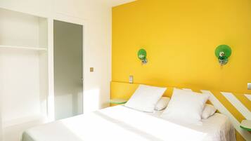 Una habitación con cama, armario y pared amarilla.