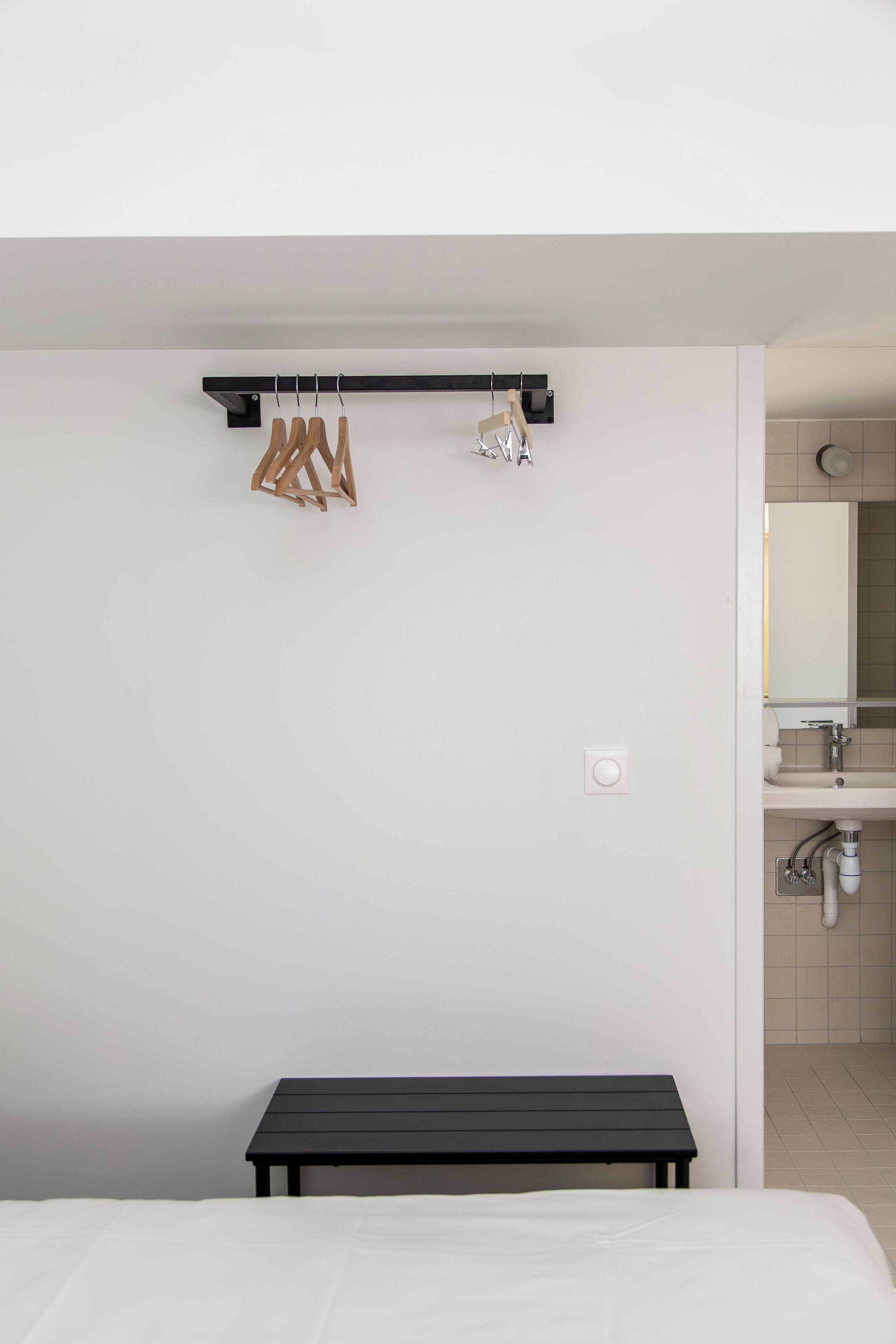 A minimalist bedroom with a bed, a black table, and a wall-mounted towel rack.