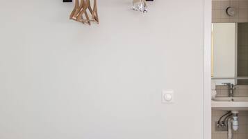 A minimalist bedroom with a bed, a black table, and a wall-mounted towel rack.