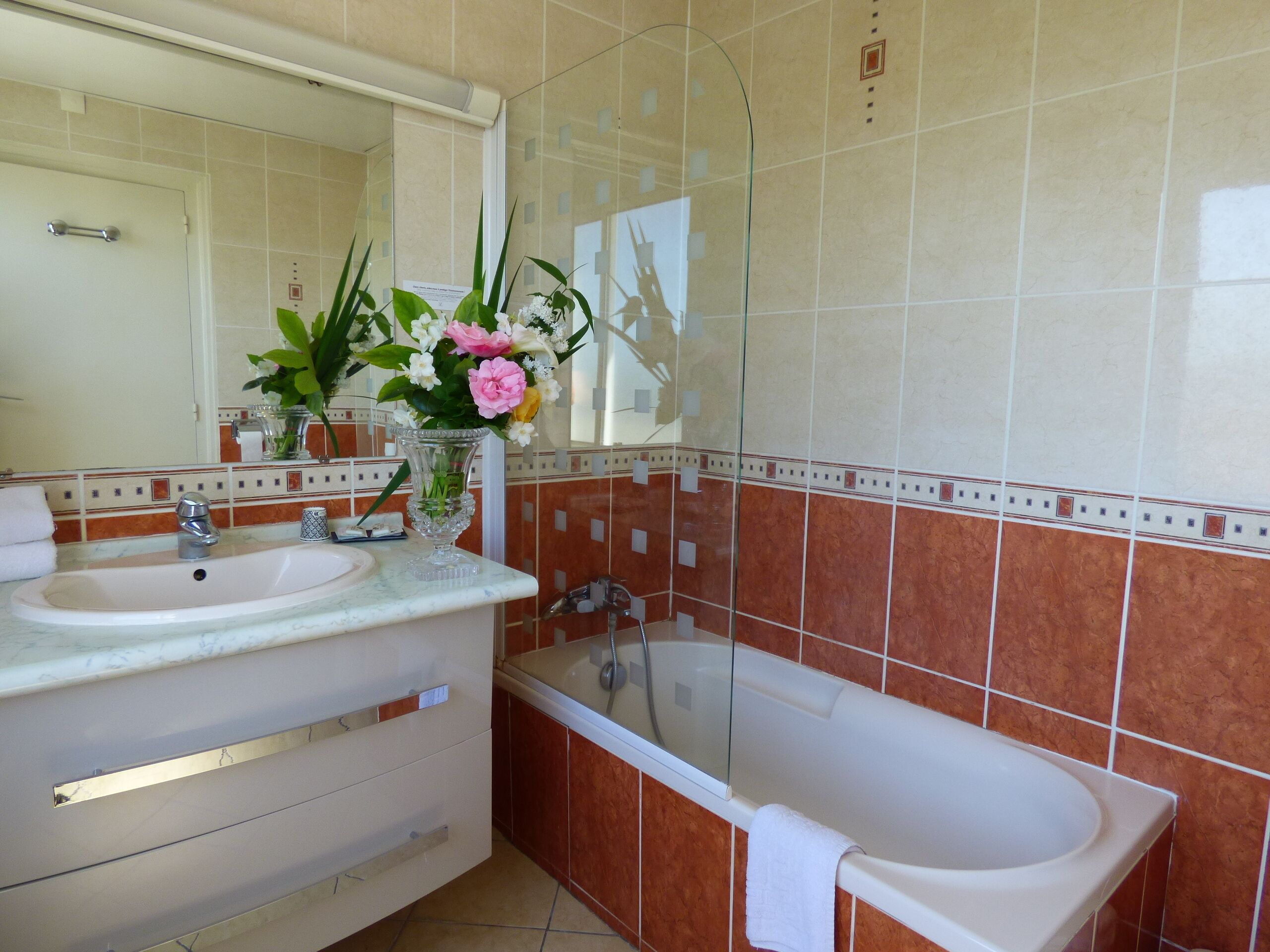 A bathroom with a sink, mirror, and bathtub.