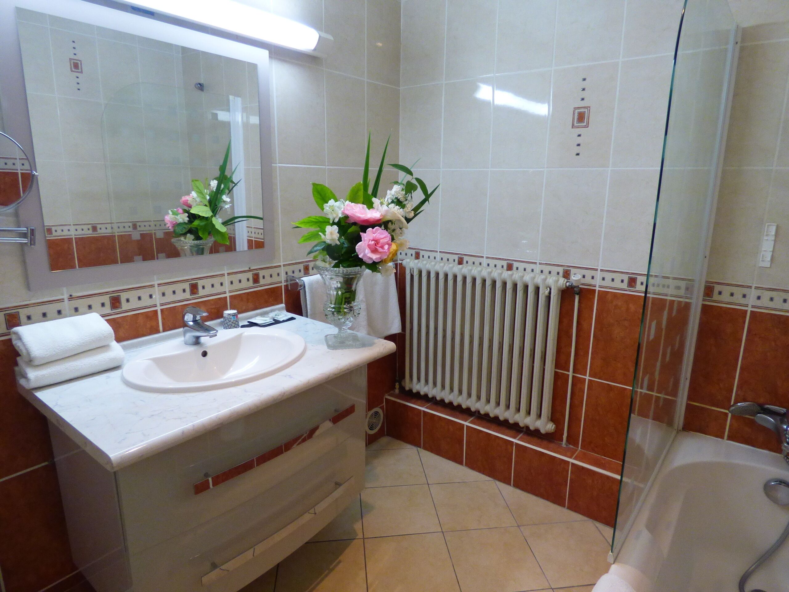 A bathroom with a sink, mirror, and a glass shower enclosure.
