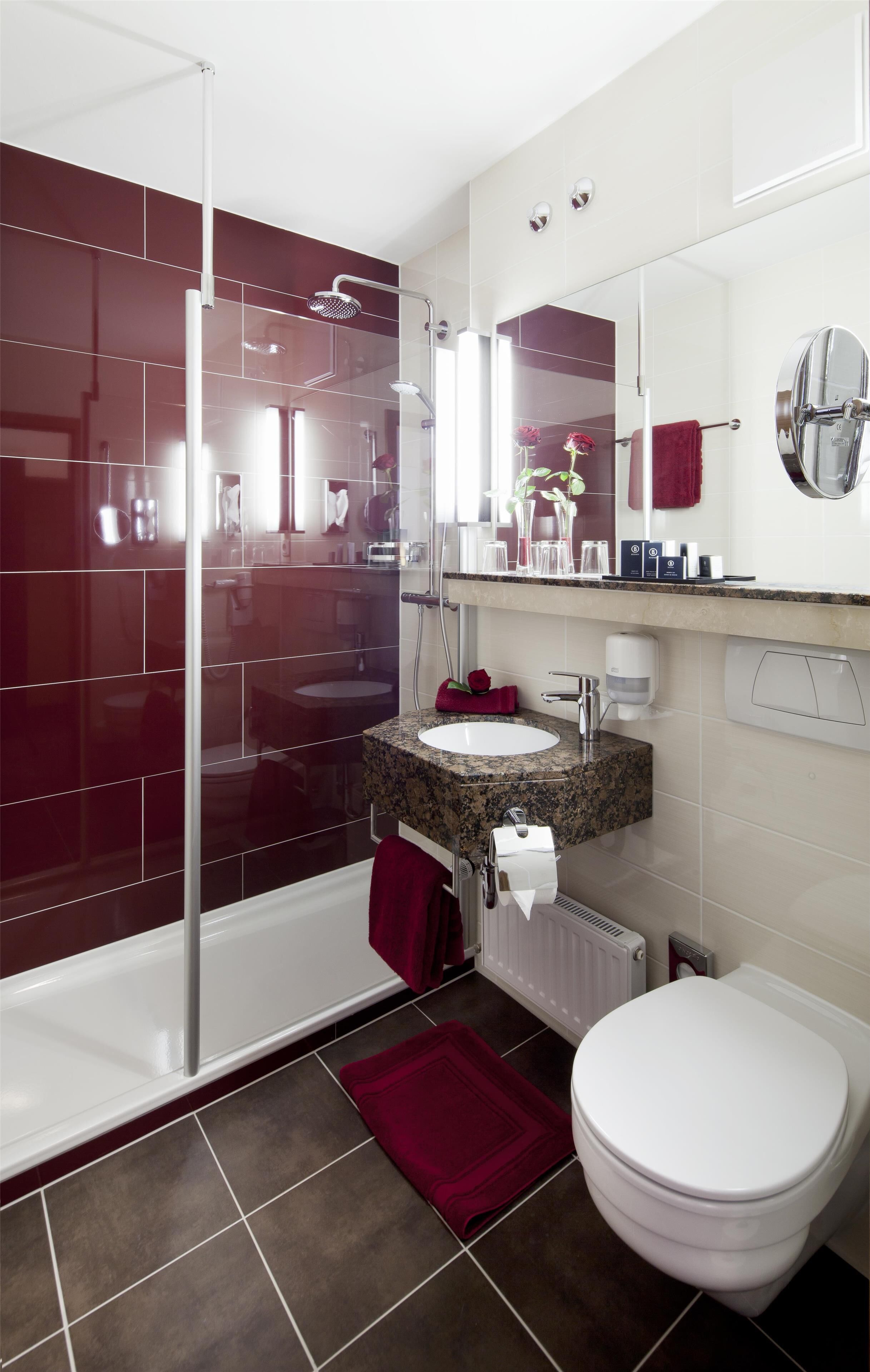 Un baño moderno con ducha envuelta en vidrio, un lavabo blanco con encimera de granito y un inodoro blanco.