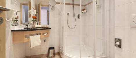 Un baño moderno con ducha de vidrio, tocador con espejo y un inodoro.