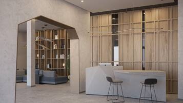 Un'accogliente area reception moderna con parete rivestita in legno, scrivania della reception, due sgabelli da bar e un angolo salotto con divano e librerie.