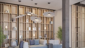 A modern living room with a sectional sofa, a large bookshelf, and pendant lighting.