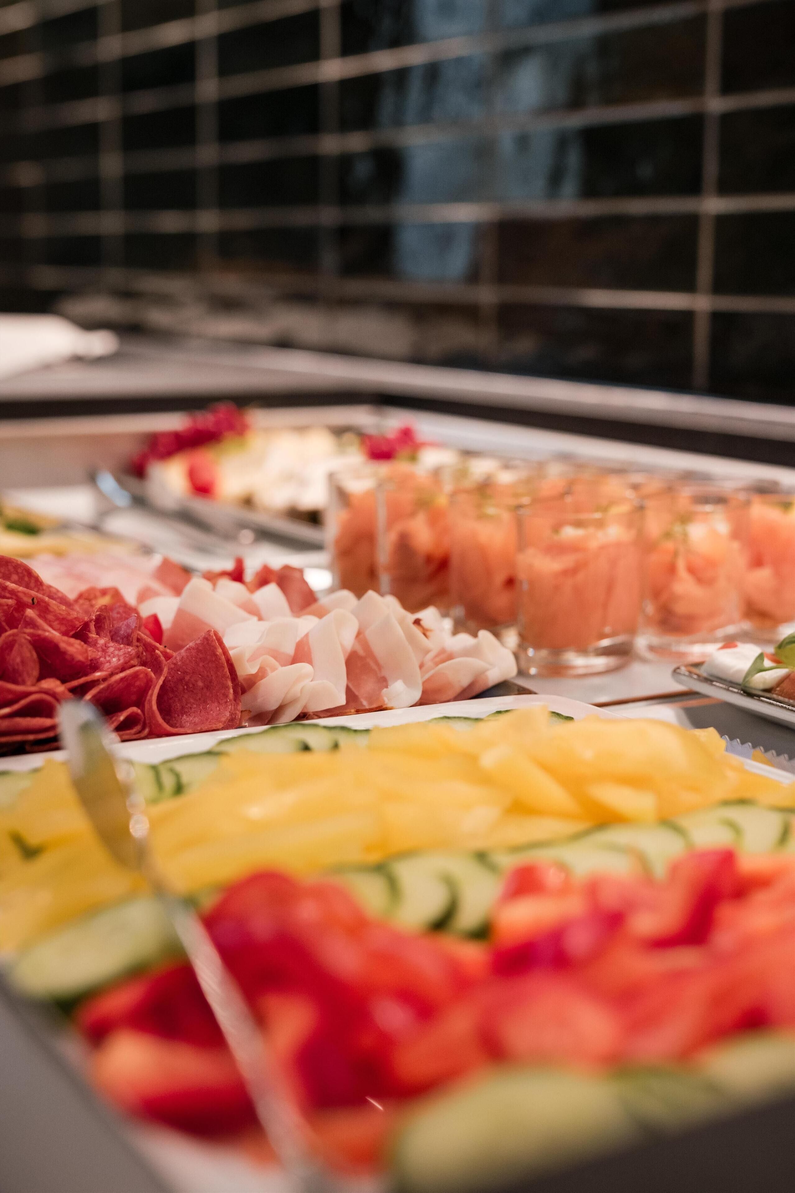 A buffet with various food options including meats, fruits, and beverages.