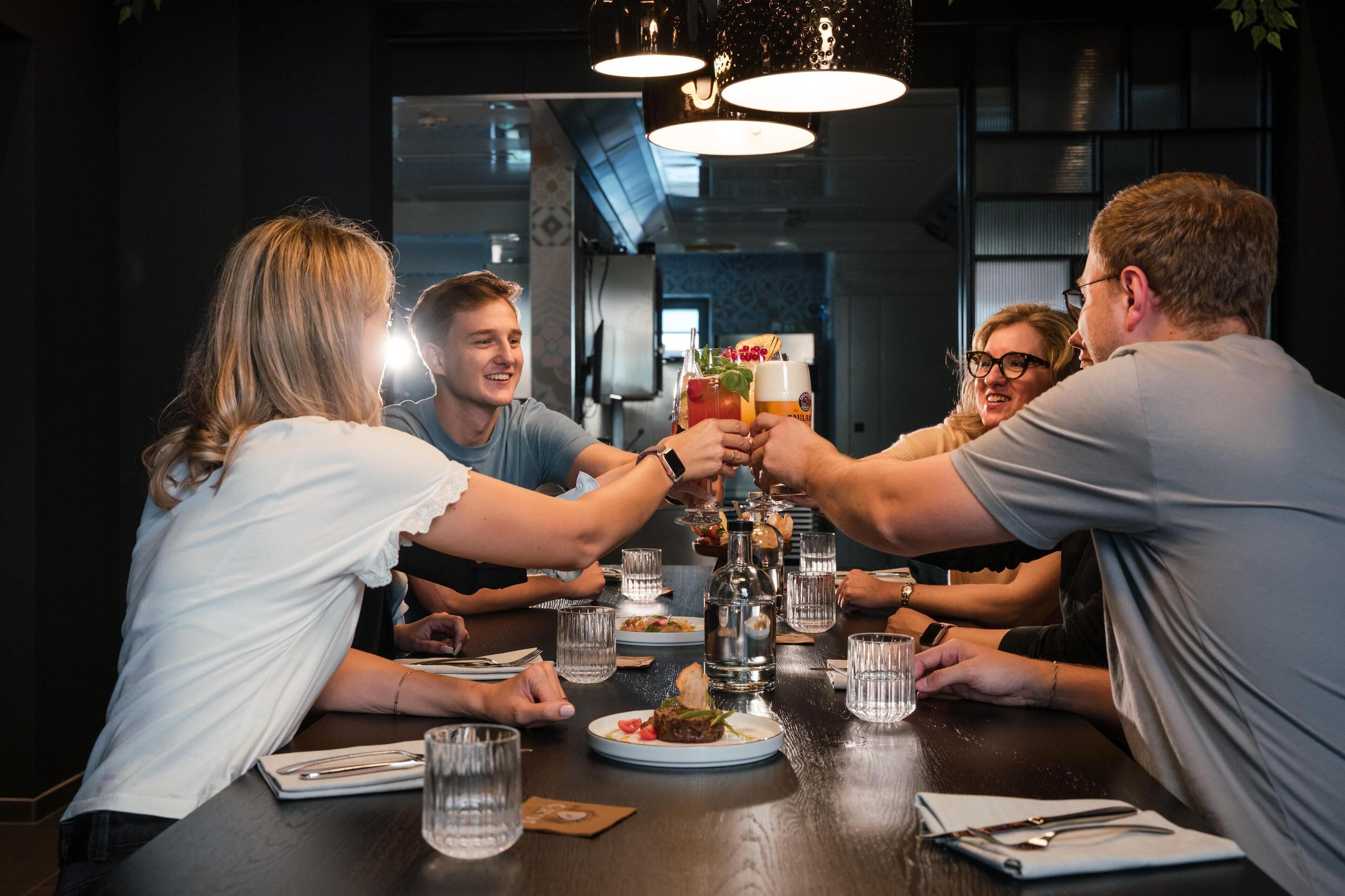 A group of people toasting at a dinner table with various dishes and drinks.