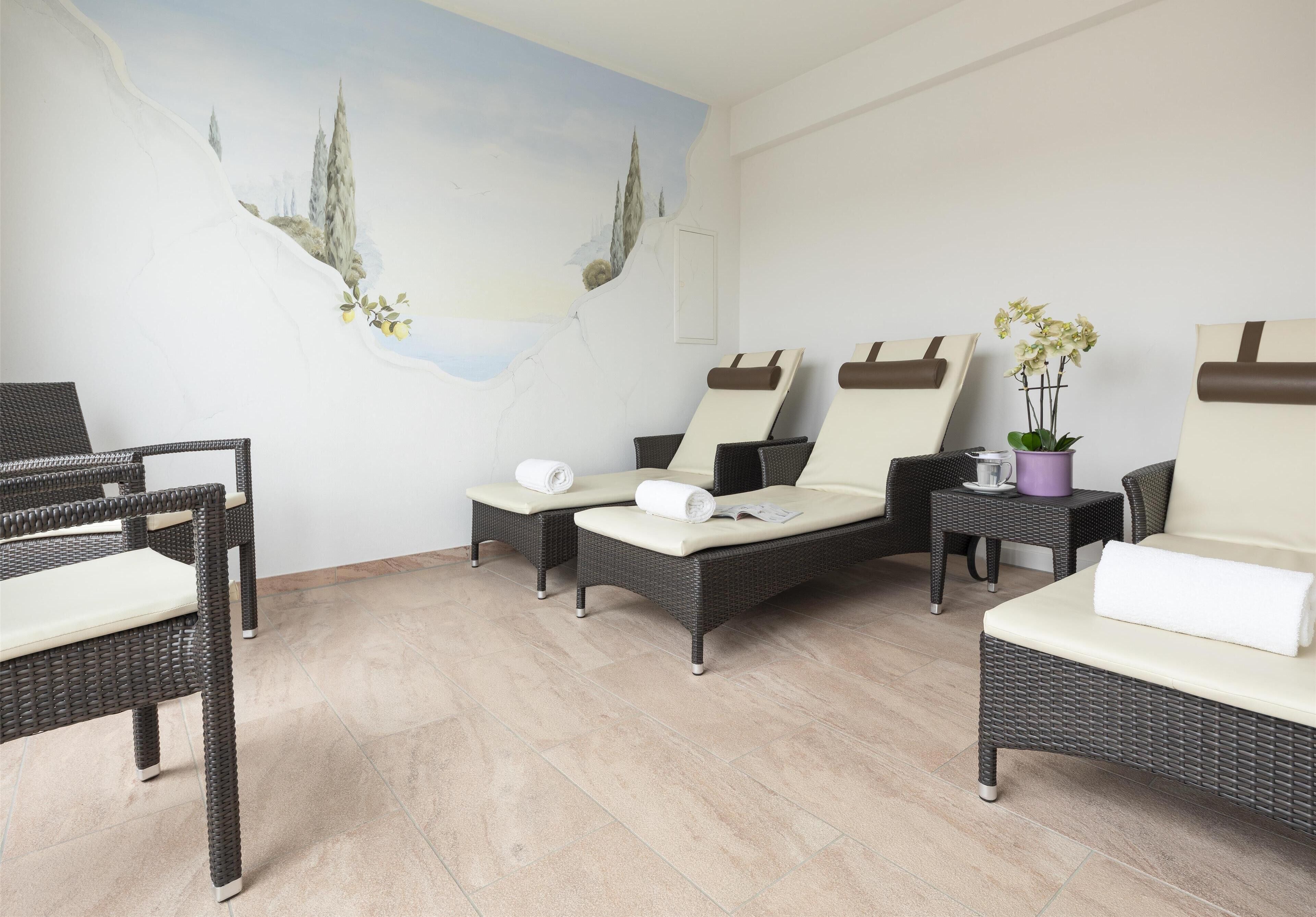 A spa room with wicker furniture, a mural, and a potted plant.