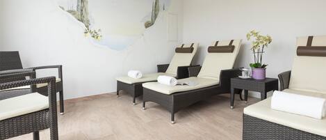 A spa room with wicker furniture, a mural, and a potted plant.