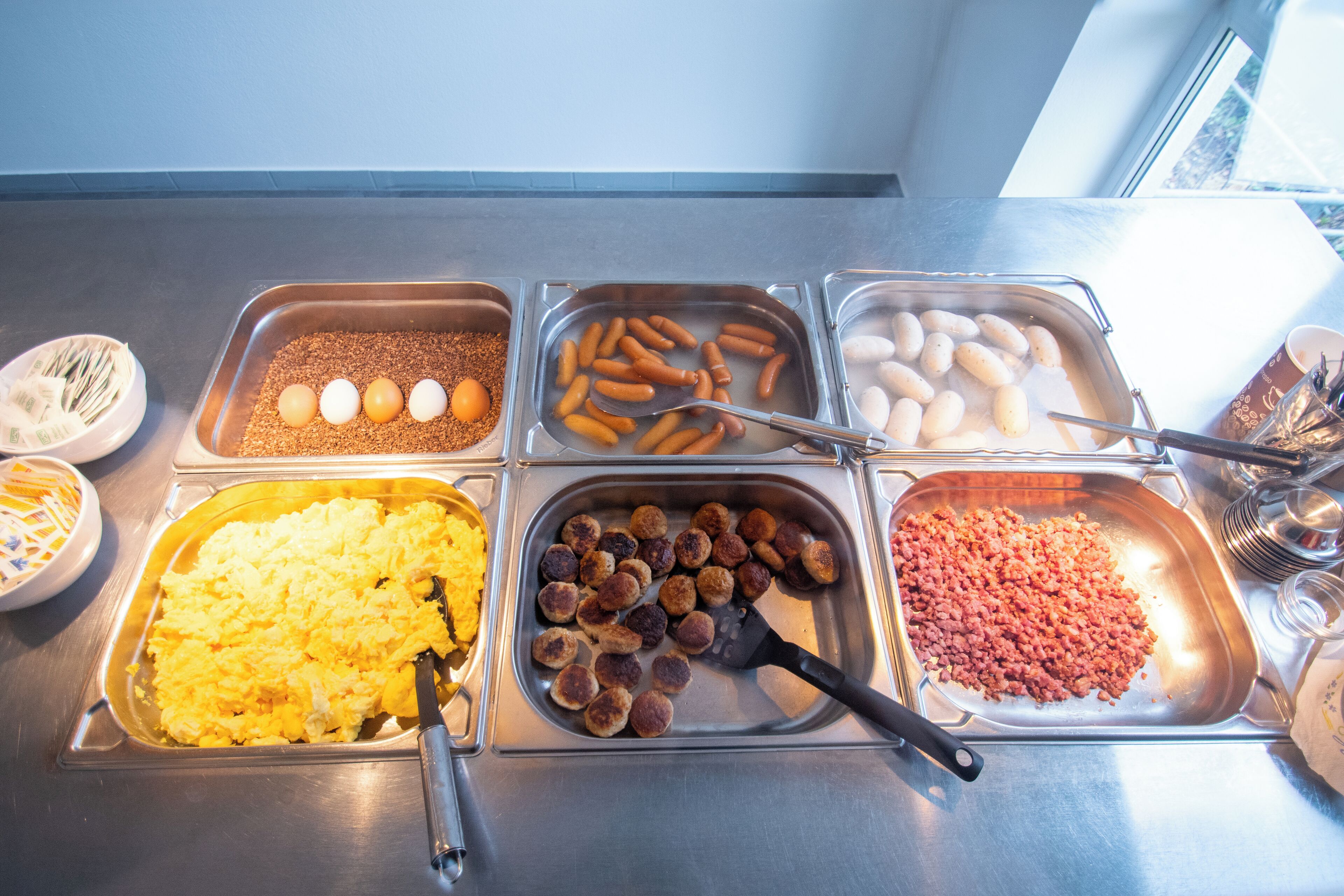 A buffet with various food items including eggs, sausages, and scrambled eggs.