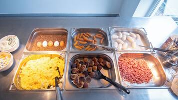 A buffet with various food items including eggs, sausages, and scrambled eggs.