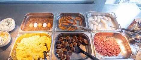 Un bufé con distintos alimentos, como huevos, salchichas y huevos revueltos.