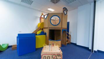 Zona de juegos con tobogán, pared de escalar y casita de madera.