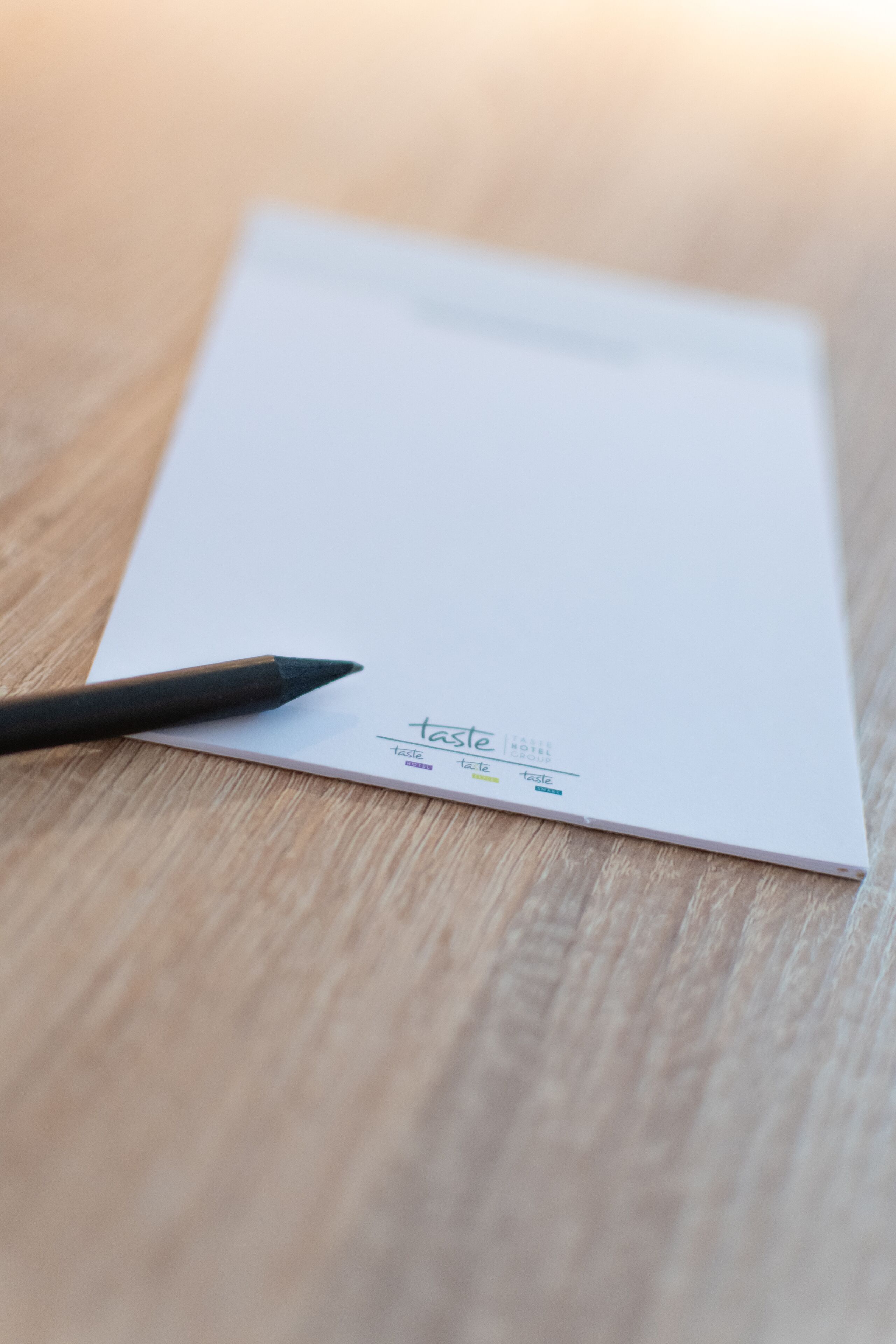 Un folleto blanco con la palabra 'taste' y algo de texto en otro idioma sobre una superficie de madera.