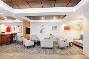 A modern lobby with a reception desk, seating area, and artwork on the walls.