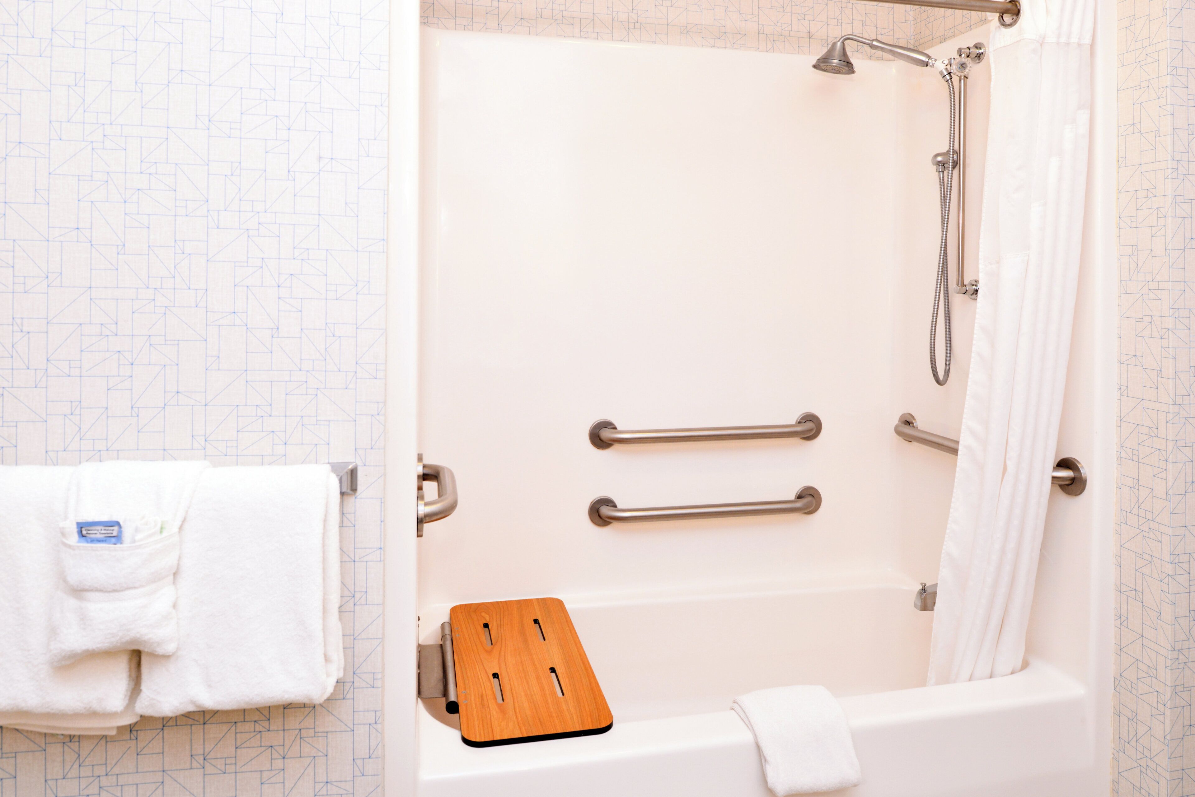 Un baño con bañera, ducha y una alfombra de baño de madera.