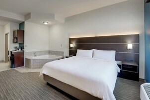 Habitación de hotel moderna con una cama grande, un baño separado con bañera, un escritorio pequeño y un aplique de pared.