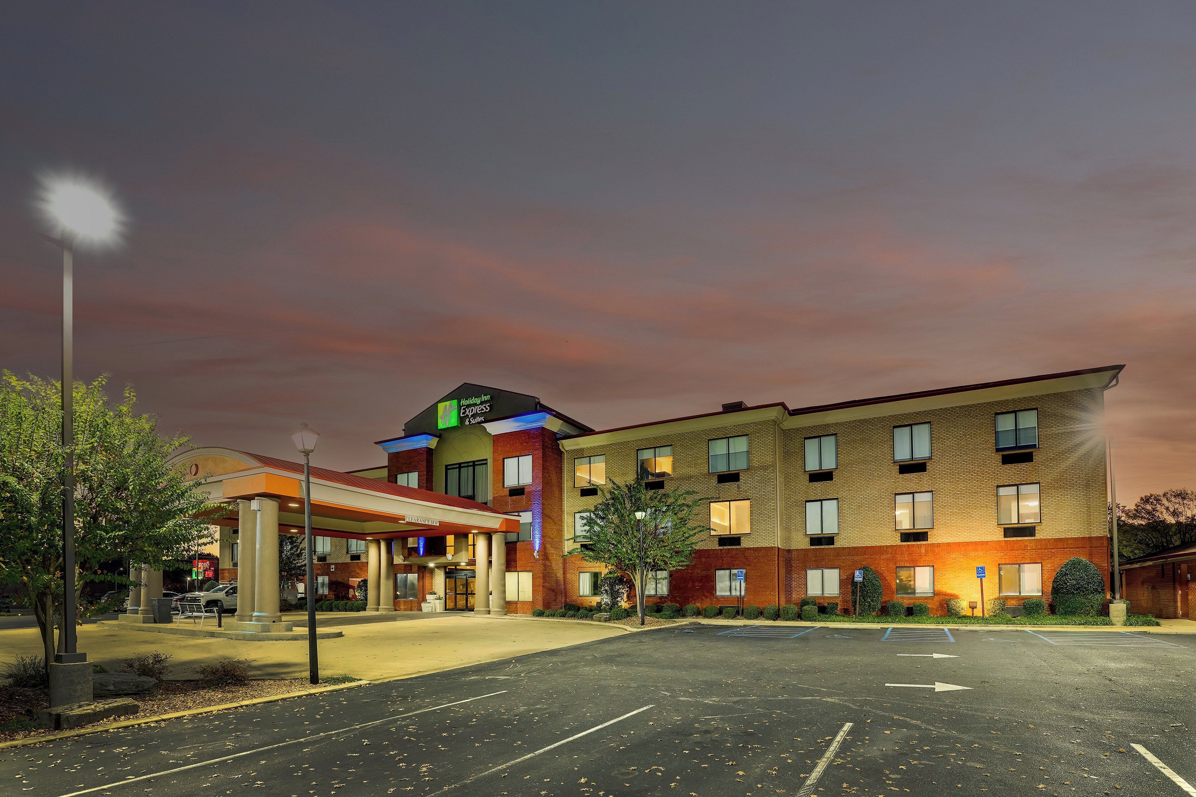 A hotel with a clear entrance, a parking lot, and a well-lit facade.