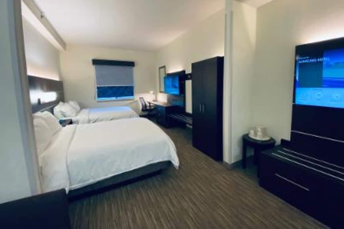 A hotel room with a bed, a desk, a TV, and a wardrobe.