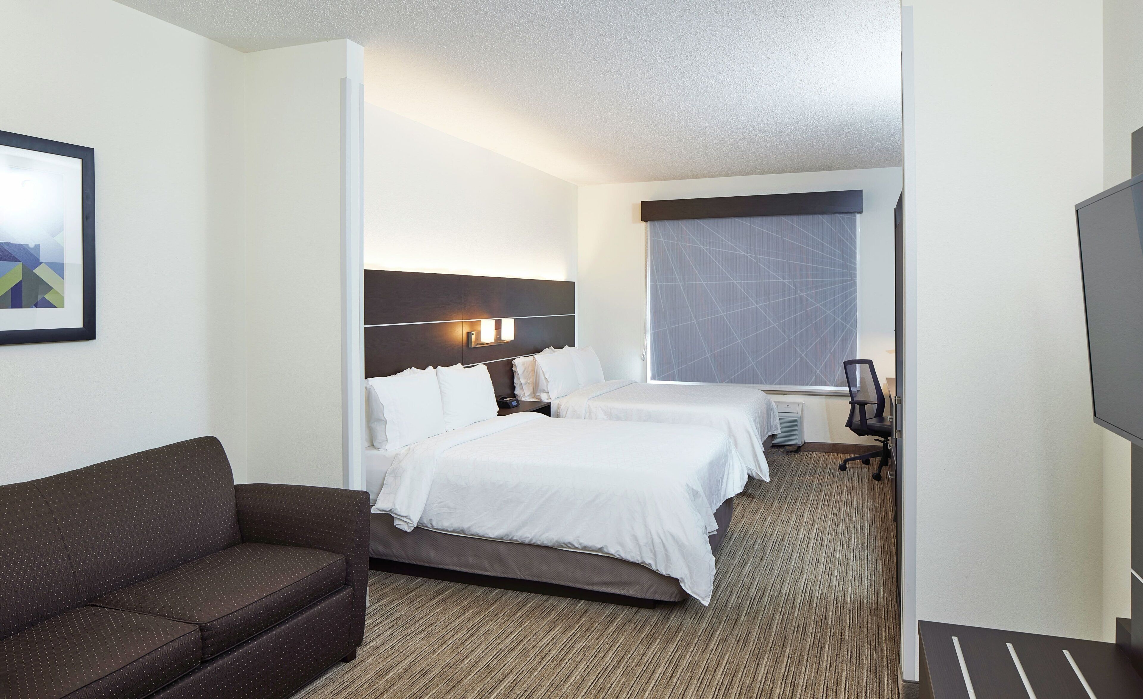Ein Hotelzimmer mit einem Bett, einer Couch, einem Schreibtisch und einem großen Fenster.