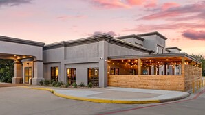 A modern building with a covered outdoor seating area, large windows, and a well-maintained entrance.
