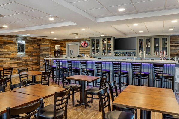 A bar area with a counter, seating, and a Coors Light refrigerator.