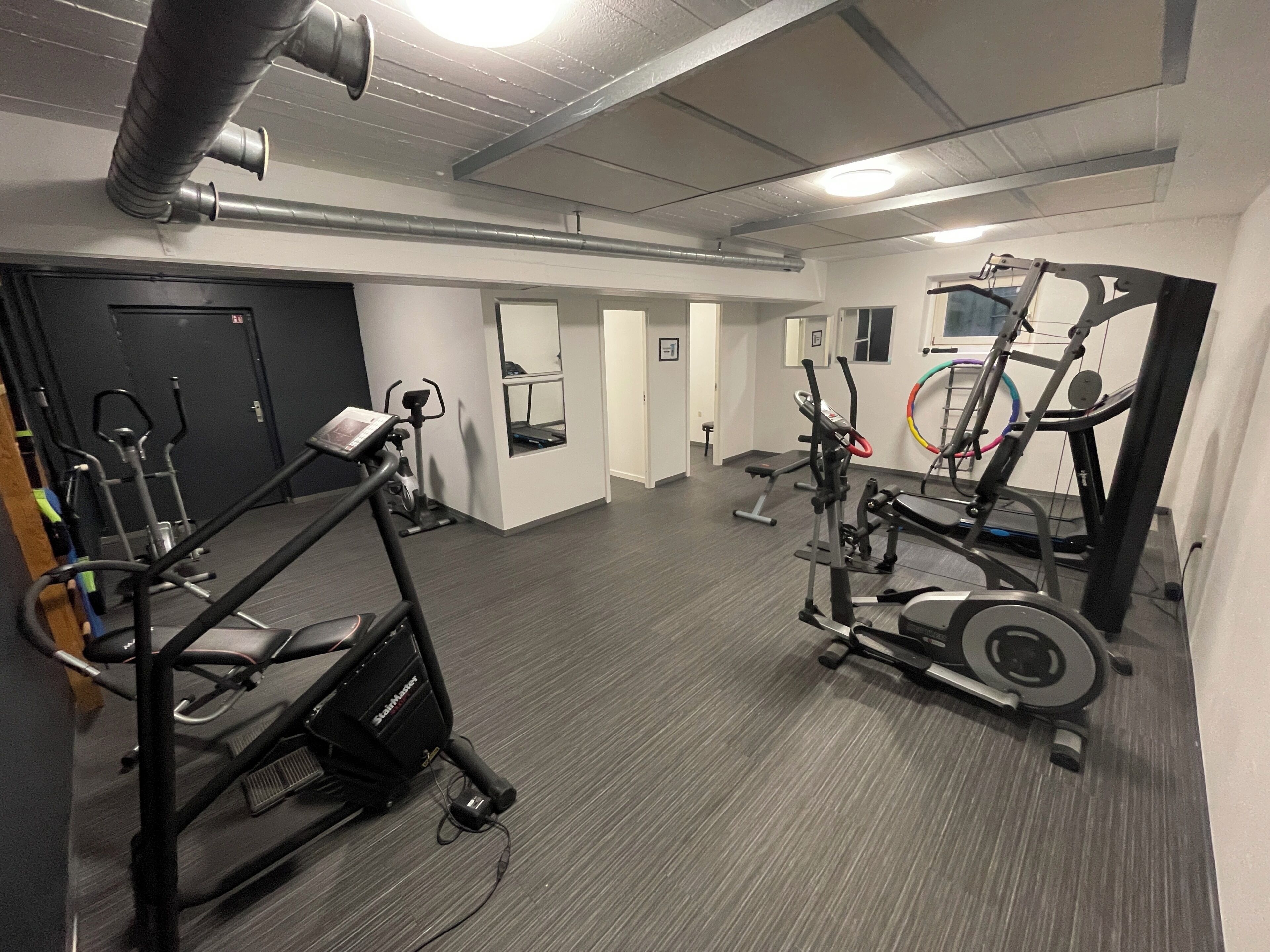 A gym with cardio machines, weight equipment, and a mirrored wall.