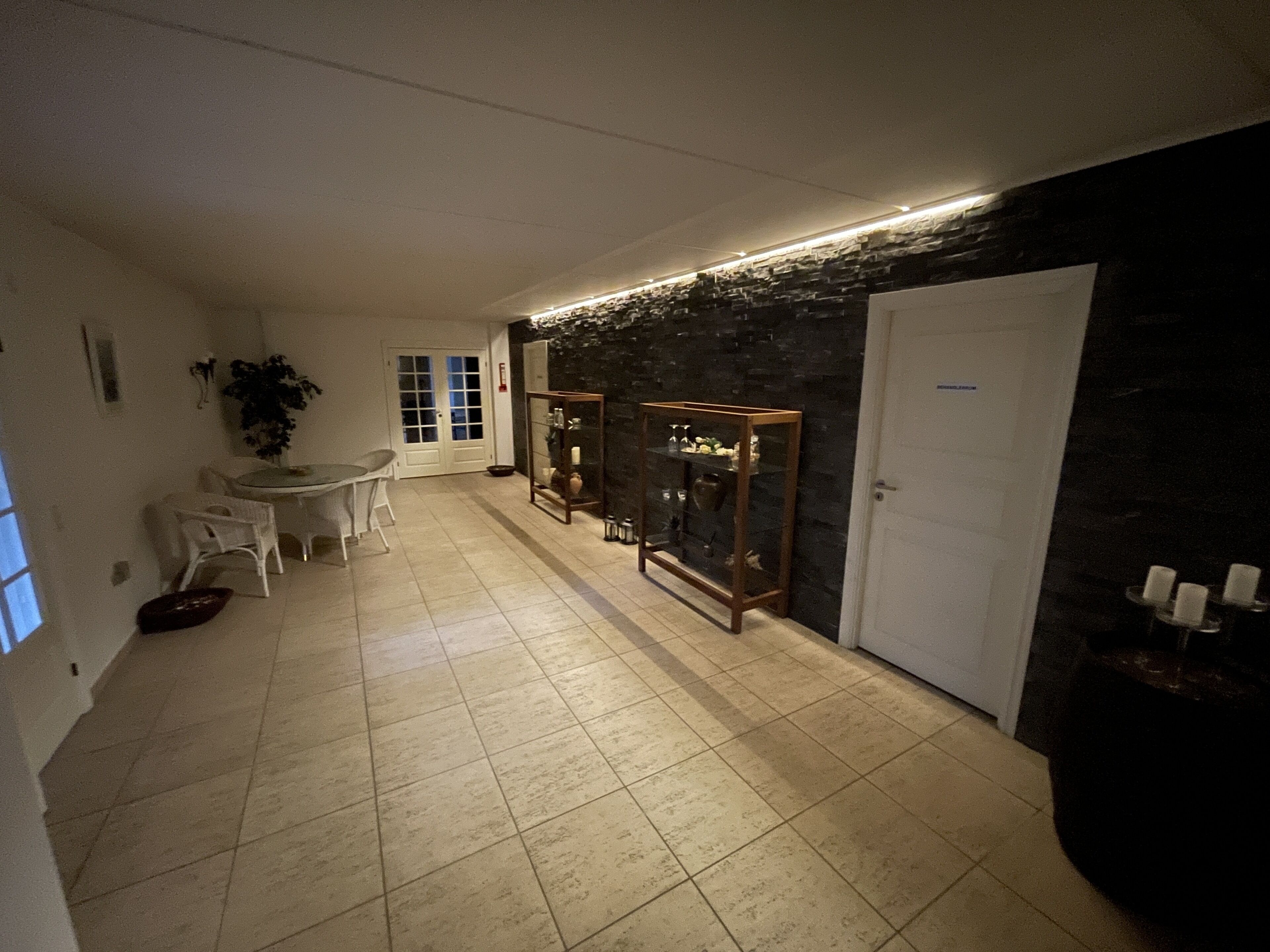 A hallway with a dining area, a black wall with a textured pattern, and a white door.